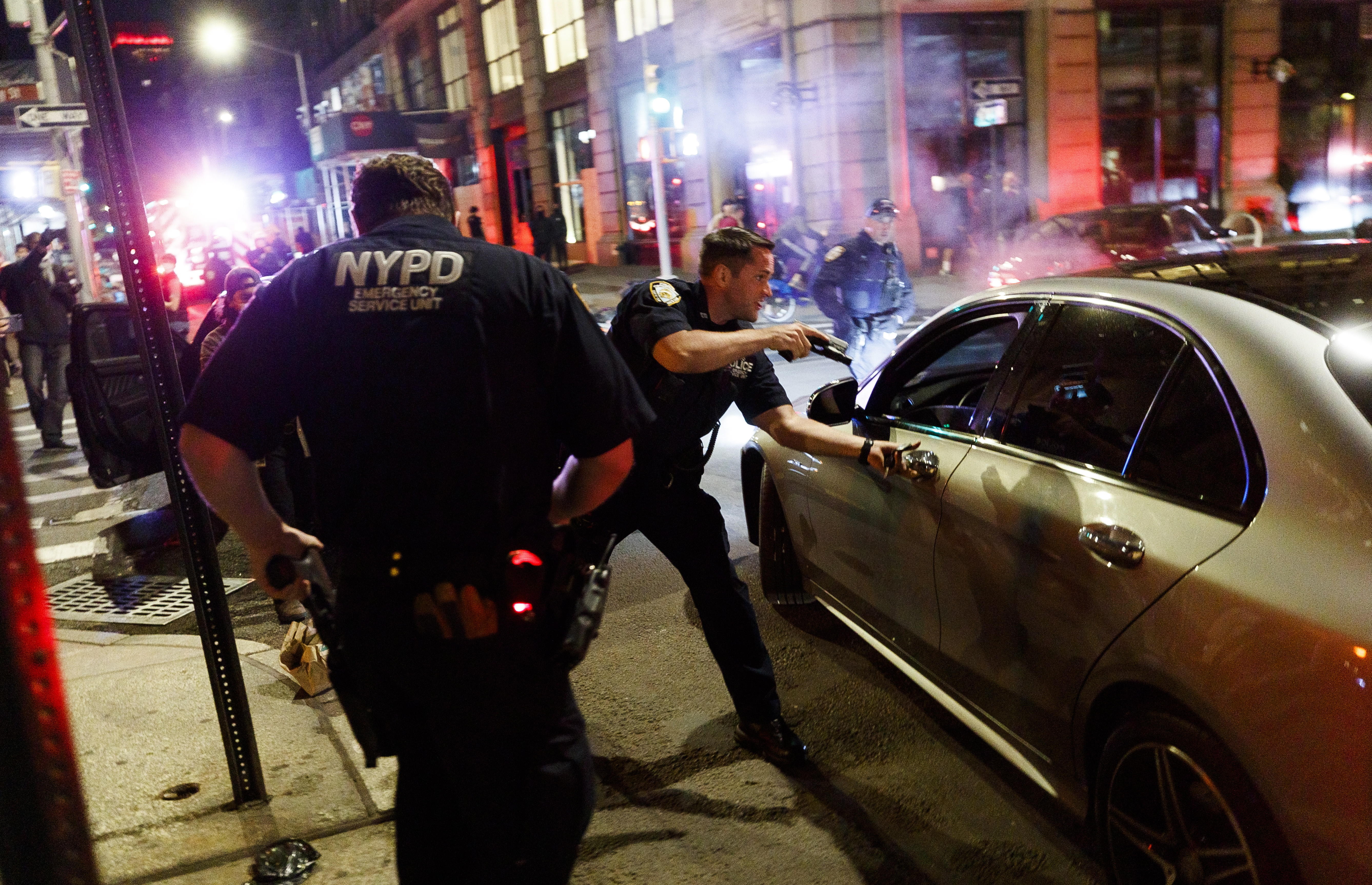 A New York police officer points his gun at a man in a car that was driving erratically and crashed into several cars in the SoHo neighborhood as people looted and vandalized stores following demonstrations over the death of George Floyd.